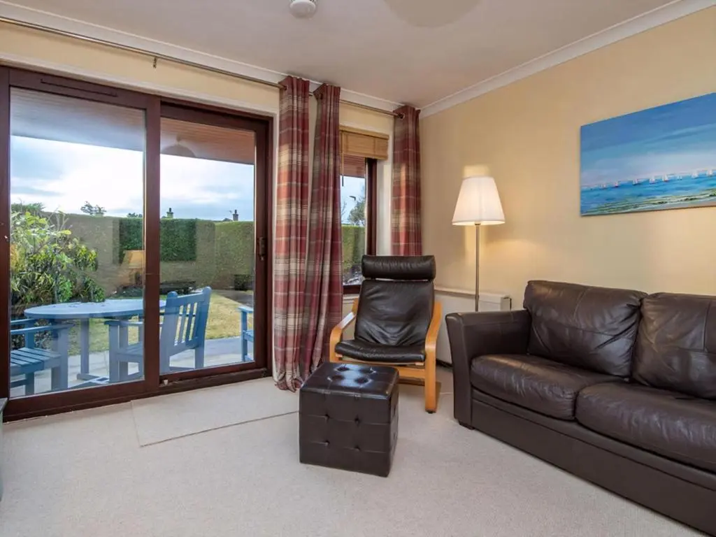 a living room with a leather couch and a sliding glass door at Strathy in Dornoch