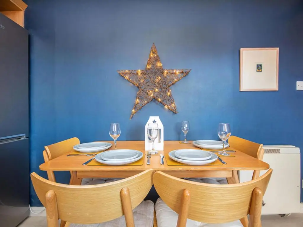 a wooden table with chairs and a star on a blue wall at Strathy in Dornoch