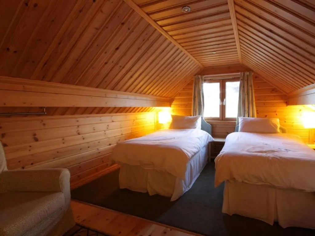 two beds in a room with wooden walls at Taigh Fiodha in Balintore