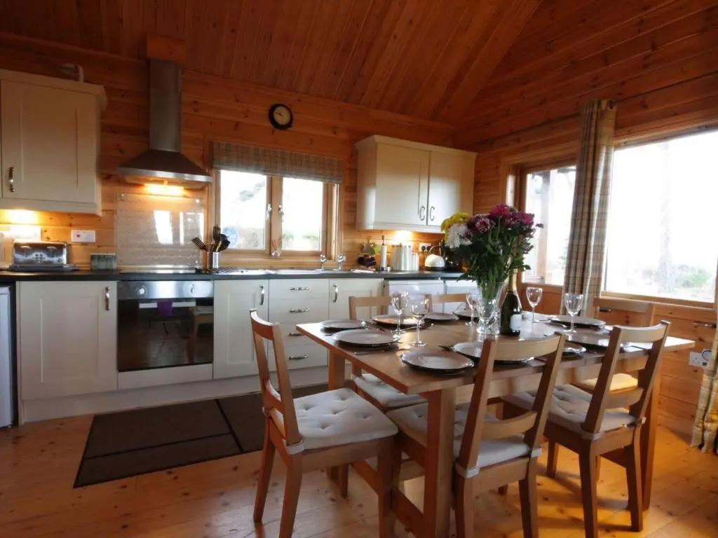 a kitchen with a dining room table with flowers on it at Taigh Fiodha in Balintore