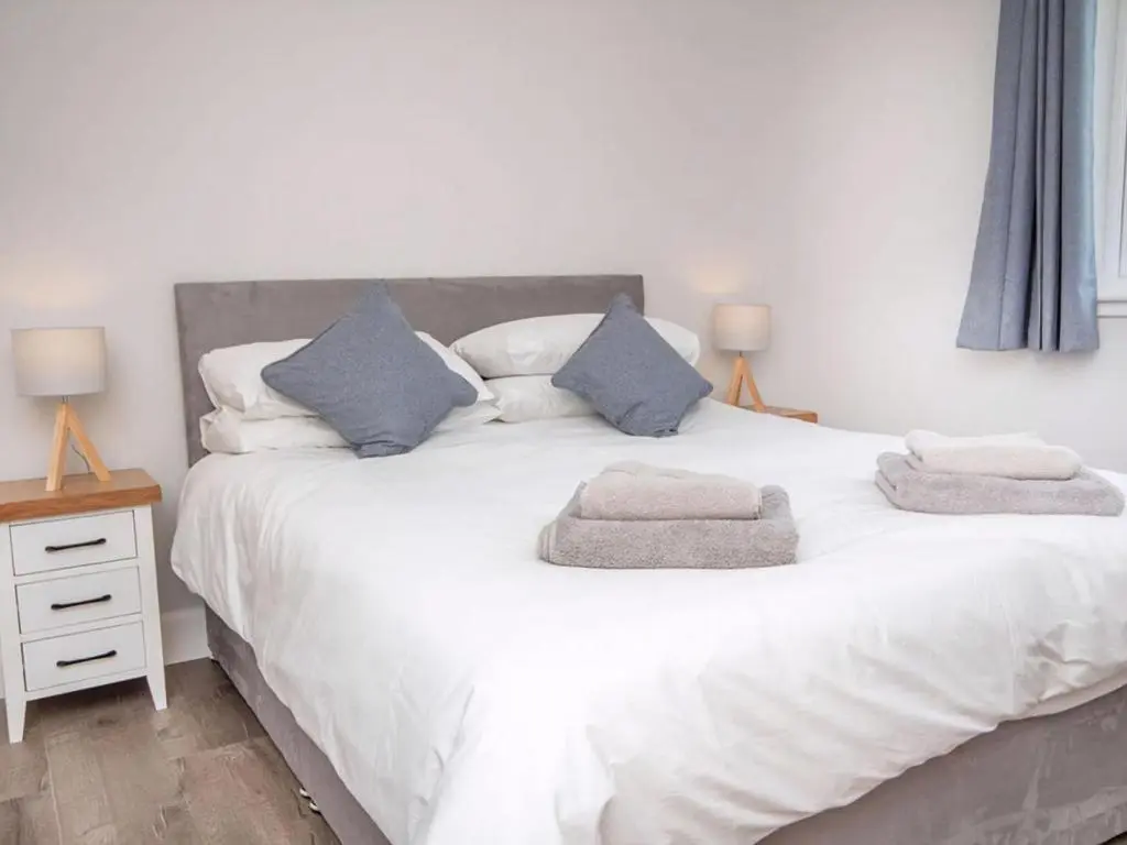 a bedroom with a white bed with two towels on it at On The Beach-Uk7465 in Balintore
