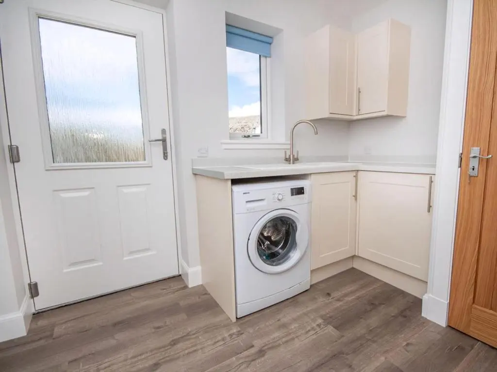 a kitchen with a washing machine and a window at On The Beach-Uk7465 in Balintore