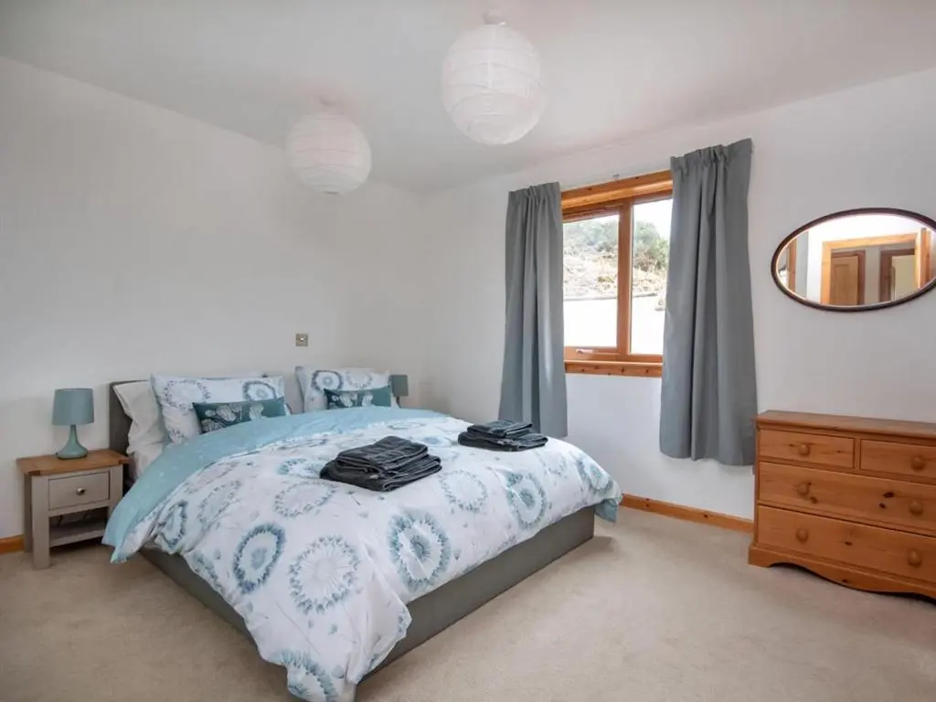 a bedroom with a bed and a mirror and a window at Lower Whinhill in Evelix