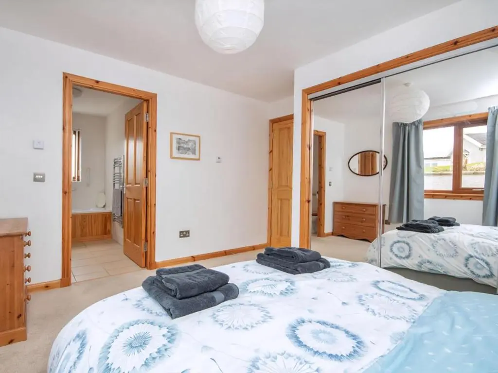 a bedroom with two beds and a mirror at Lower Whinhill in Evelix