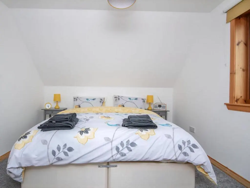 a white bedroom with a bed with a white wall at Lower Whinhill in Evelix