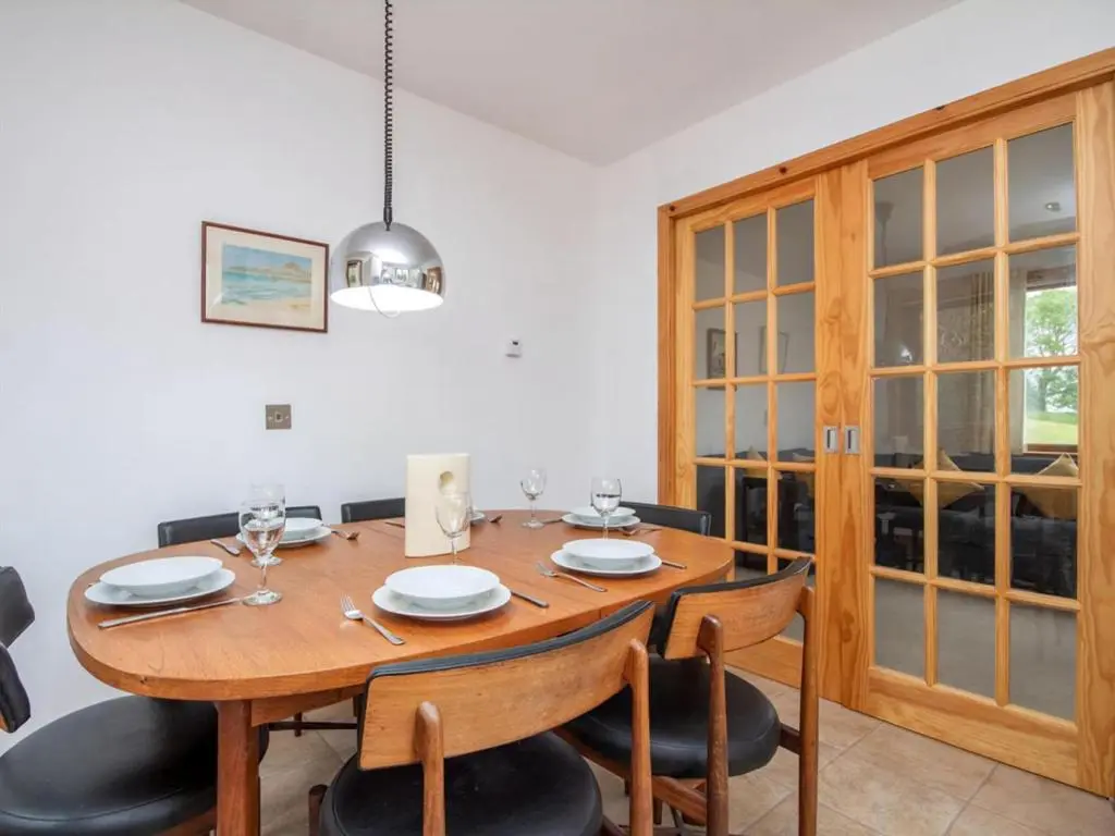 a dining room with a wooden table and chairs at Lower Whinhill in Evelix