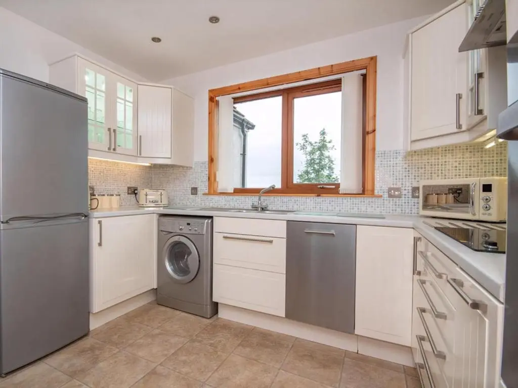 a kitchen with white cabinets and a dishwasher at Lower Whinhill in Evelix
