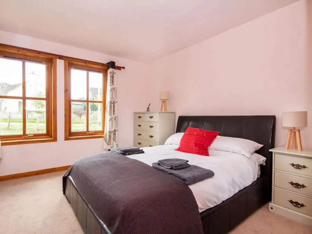 a bedroom with a bed with red pillows on it at Fernabeg in Edderton