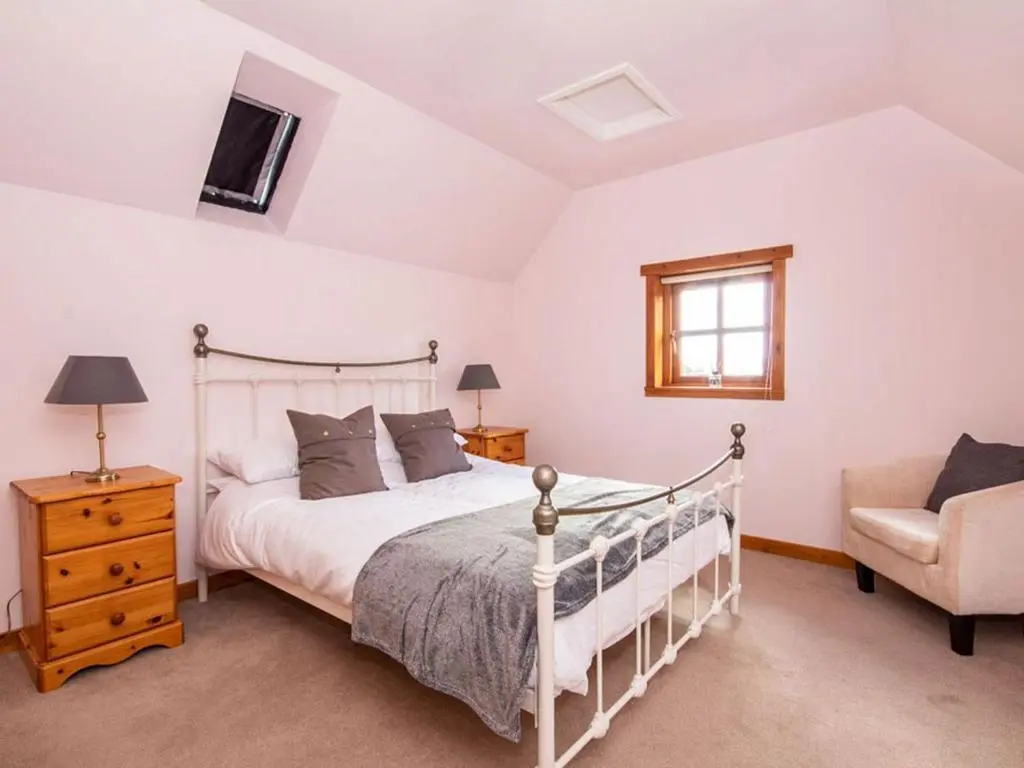 a bedroom with a white bed and a chair at Fernabeg in Edderton