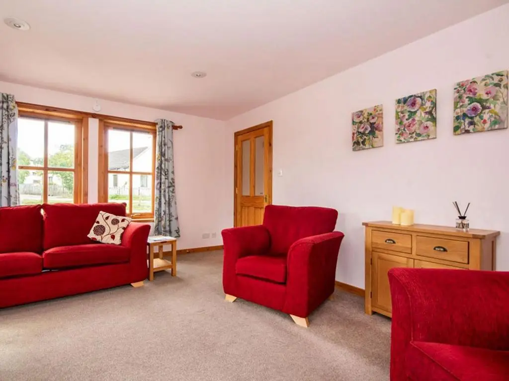 a living room with two red chairs and a window at Fernabeg in Edderton
