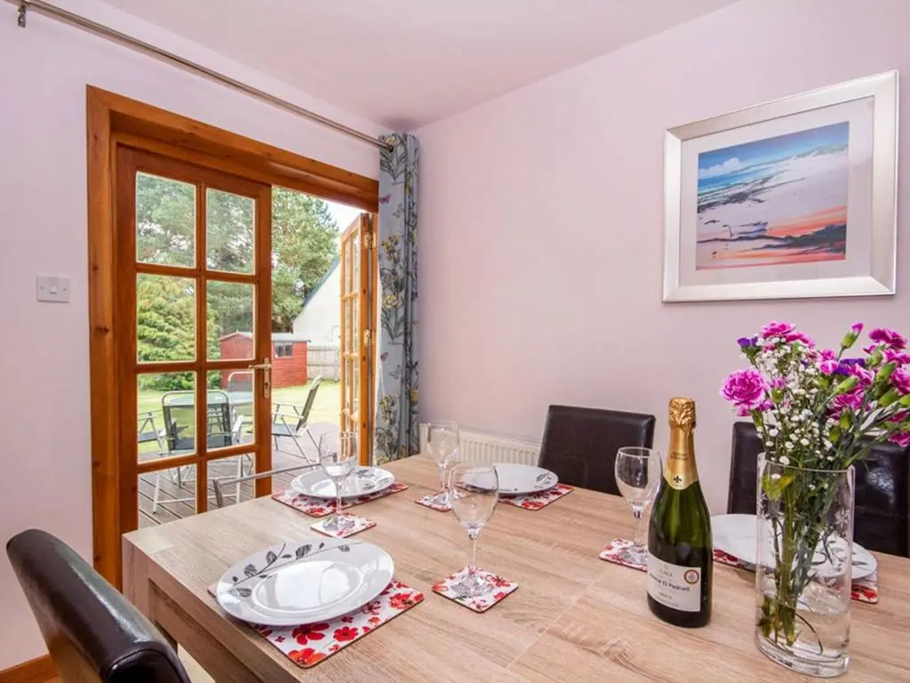 a dining room table with a bottle of wine and glasses at Fernabeg in Edderton