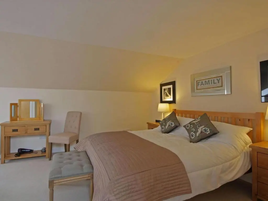 a bedroom with a large bed and a chair at Fairway Apartment in Nairn