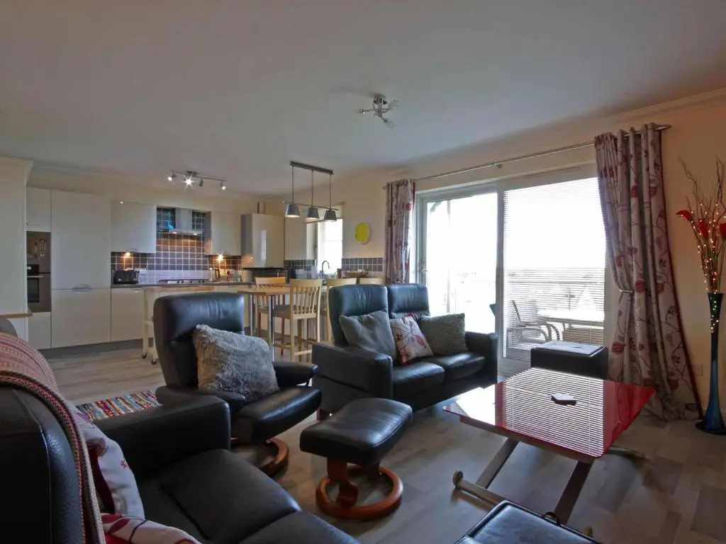 a living room with a couch and chairs and a kitchen at Fairway Apartment in Nairn