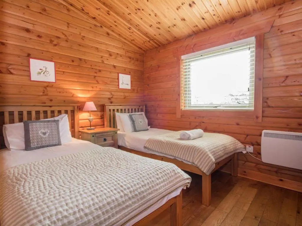 a bedroom with two beds in a wooden cabin at Gael Cham in Aviemore