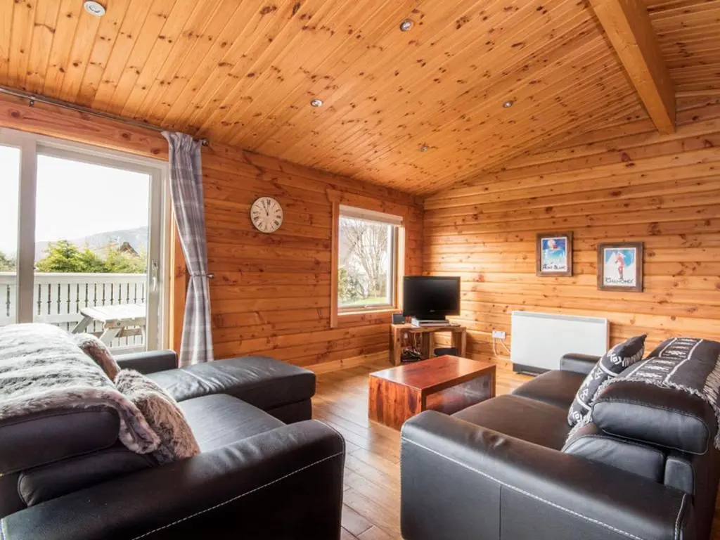 a living room with leather couches and a television at Carn Eilrig in Aviemore