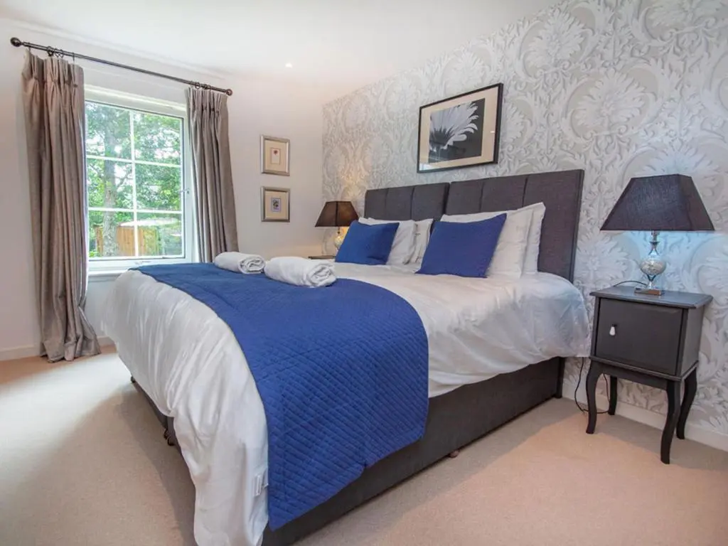 a bedroom with a large bed with blue and white sheets at The Steading Apartment, No9 in Aviemore