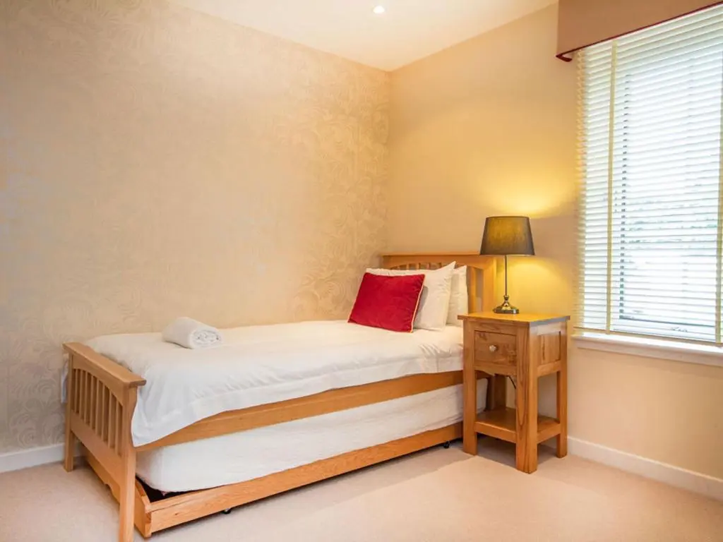 a bedroom with a bed with a red pillow on it at The Steading Apartment, No9 in Aviemore