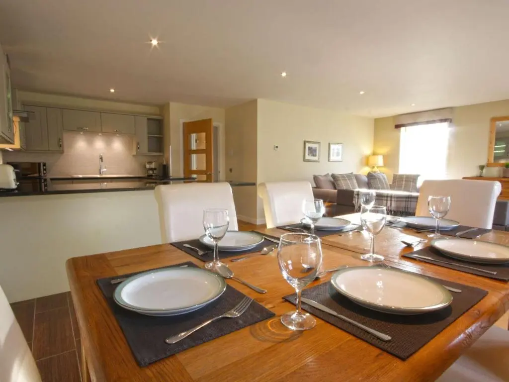 a wooden table with plates and wine glasses on it at The Steading Apartment, No9 in Aviemore