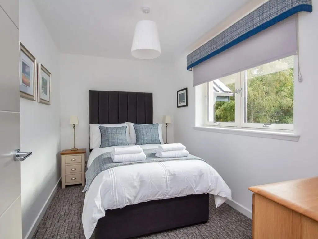 a bedroom with a large bed and a window at Oakwood in Aviemore