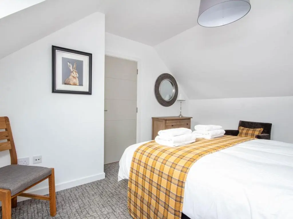 a bedroom with a bed and a chair and a mirror at Oakwood in Aviemore