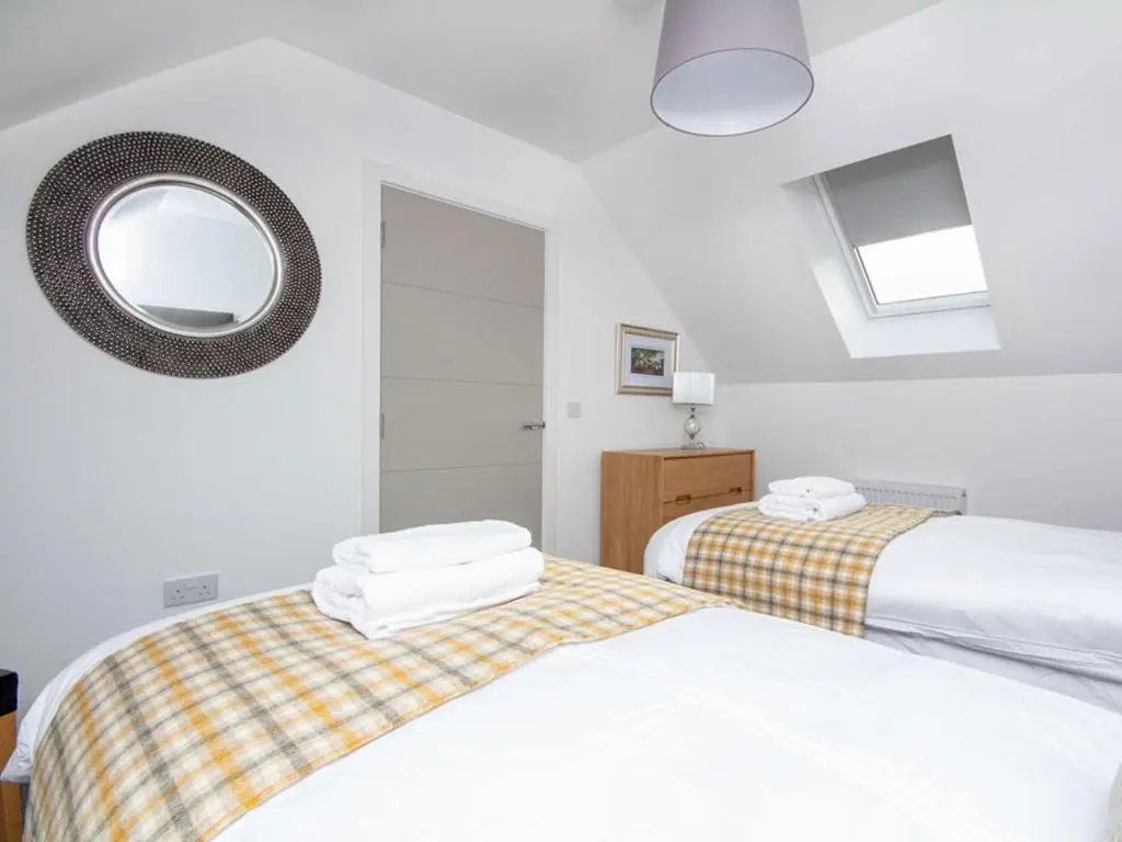 a bedroom with two beds and a mirror at Oakwood in Aviemore