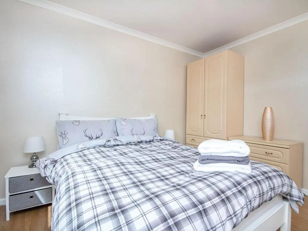 a bedroom with a bed with a plaid blanket at Caledon in Aviemore