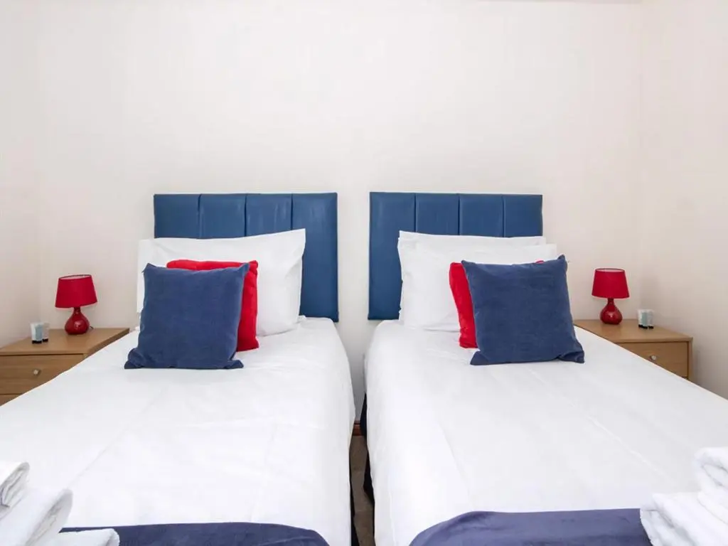 two beds in a room with red and blue pillows at Holm Dell Apartment in Inshes