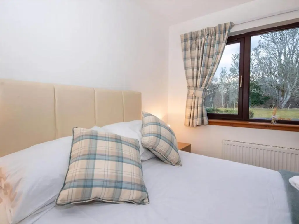 a bedroom with a bed with two pillows and a window at Holm Dell Apartment in Inshes