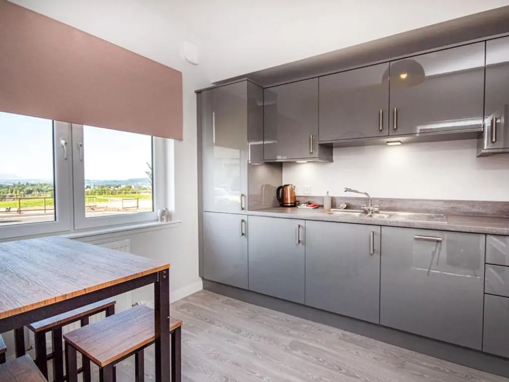 a kitchen with gray cabinets and a table and a window at Kessock View Apartment in Inshes