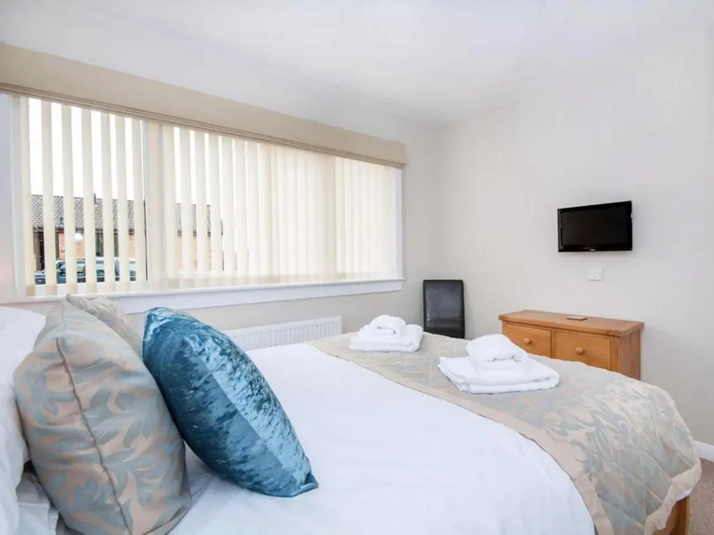a bedroom with a bed with blue pillows and a television at 58 Moray Park in Culloden