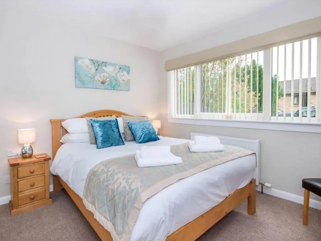a bedroom with a large bed with blue pillows at 58 Moray Park in Culloden