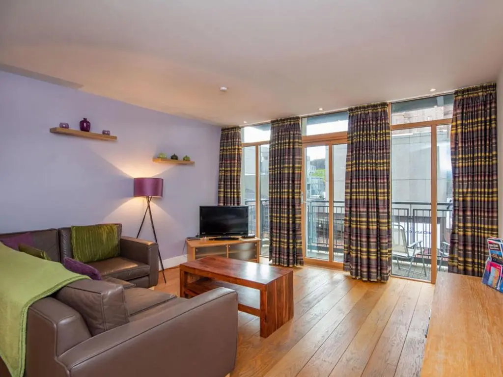 a living room with a couch and a tv at 206 By The Bridge Apartment in Inverness