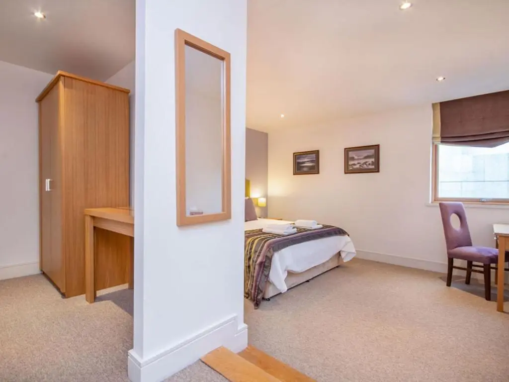 a bedroom with a bed and a desk and a mirror at 206 By The Bridge Apartment in Inverness