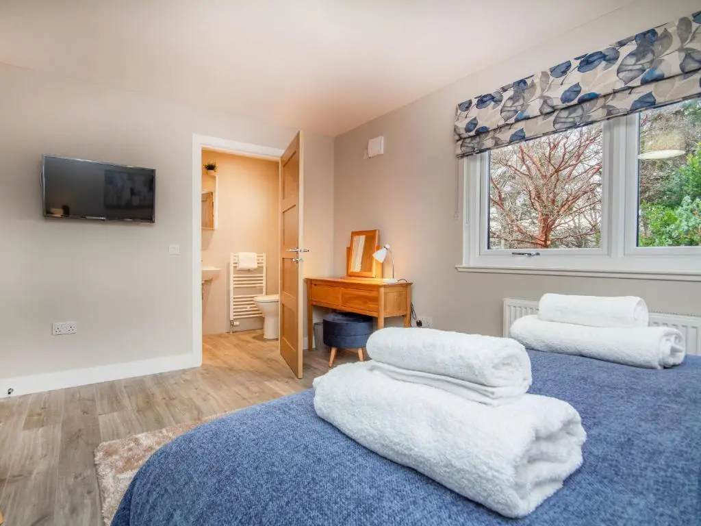 two beds in a room with a desk and a window at Sunnyside Culloden in Inverness
