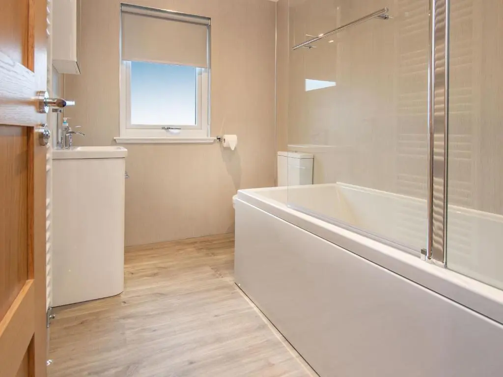 a white bathroom with a tub and a window at Sunnyside Culloden in Inverness