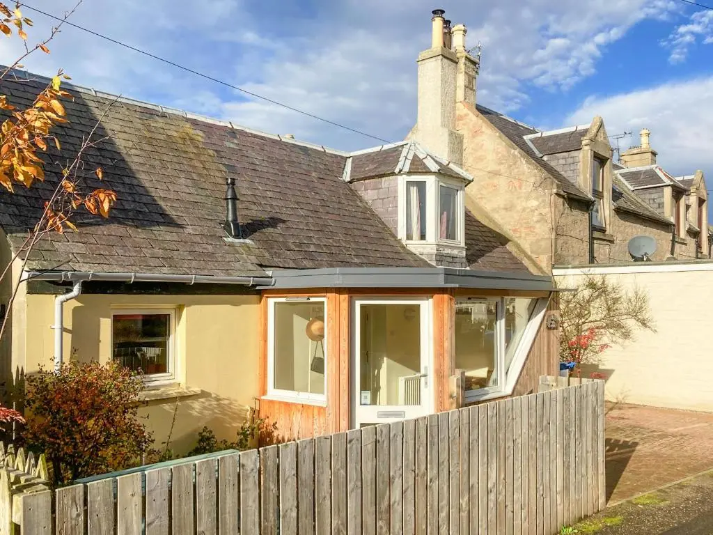 a house with a wooden fence in front of it at Isla's Cottage in Nairn