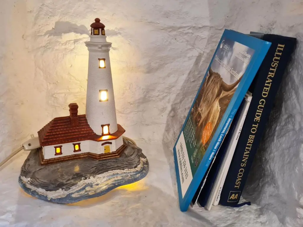 a model of a lighthouse sitting next to a book at Isla's Cottage in Nairn