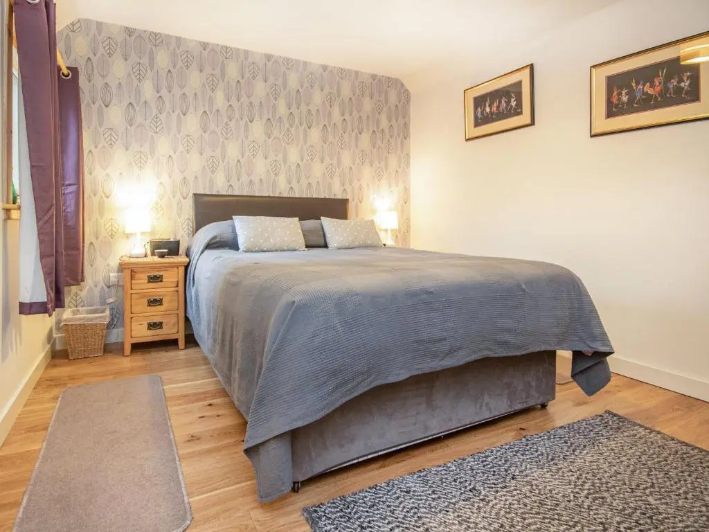a bedroom with a large bed and a night stand at Isla's Cottage in Nairn