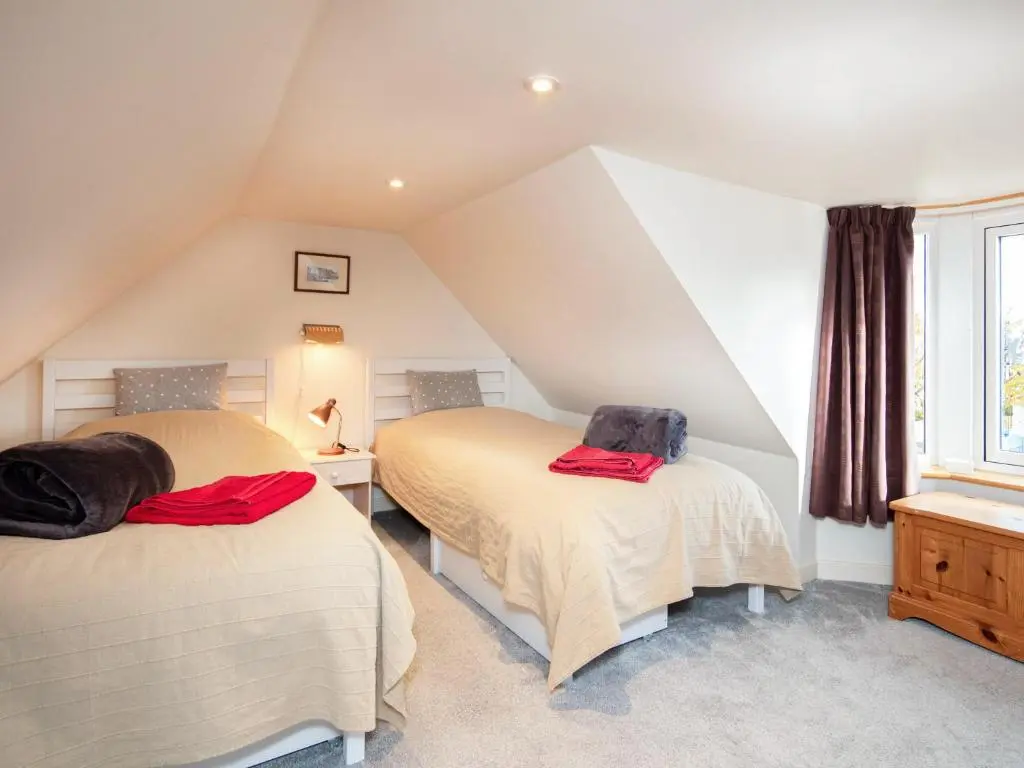 two beds in a attic room with a window at Isla's Cottage in Nairn