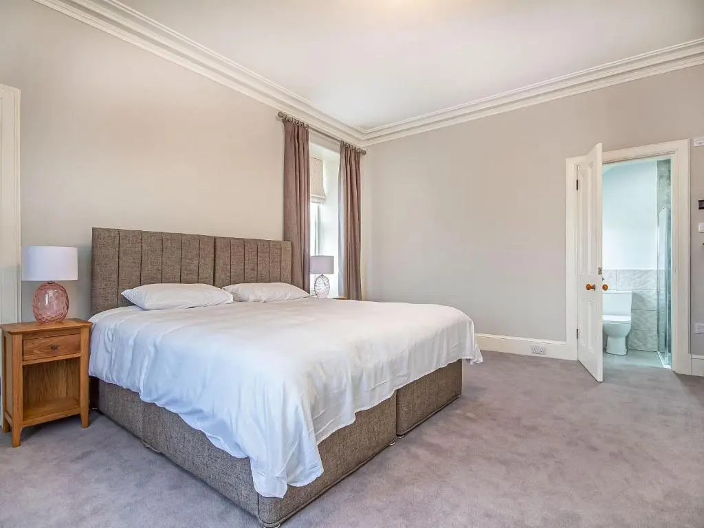 a white bedroom with a large bed and a window at Reay House in Nairn