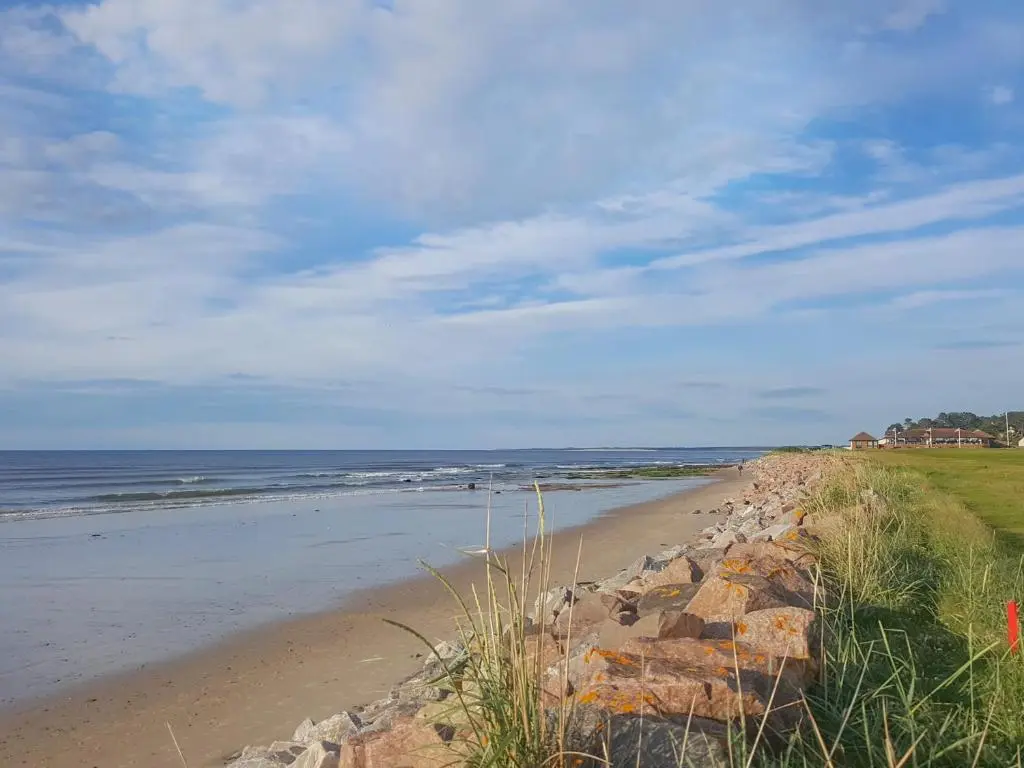 a beach with rocks and the ocean on a cloudy day at Reay House in Nairn