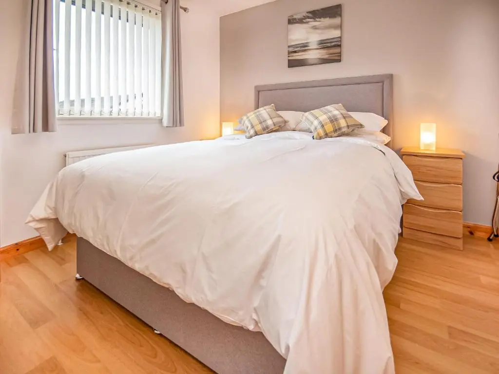 a bedroom with a large bed with white sheets and pillows at Bow Fiddle in Nairn