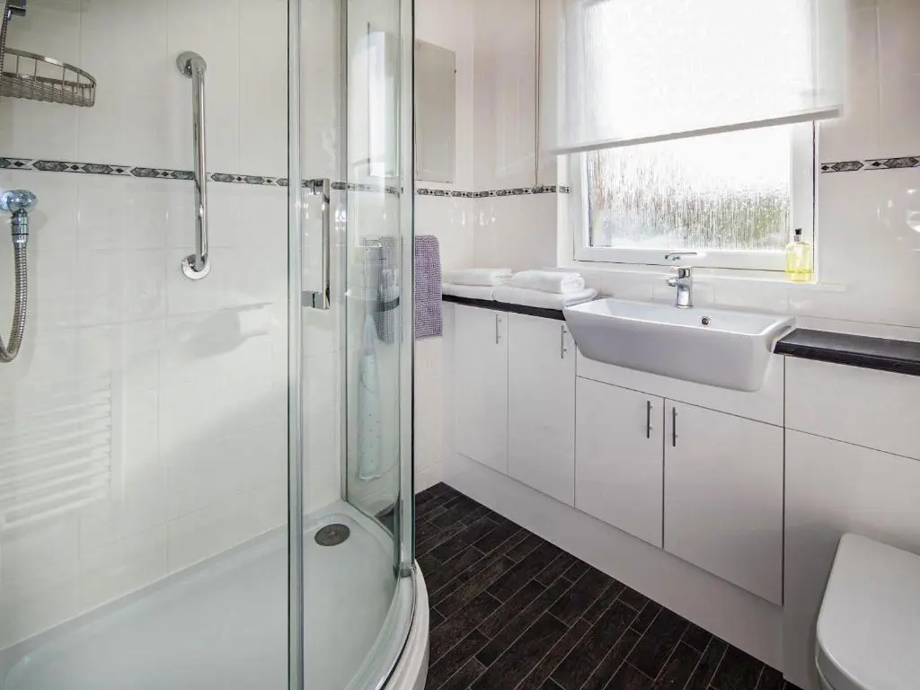 a white bathroom with a sink and a shower at Bow Fiddle in Nairn