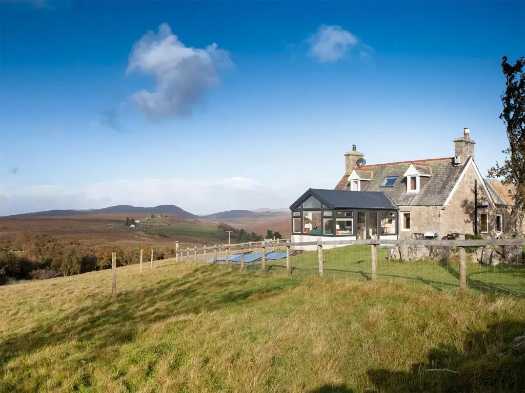 a house on a hill with mountains in the background at Smithy Burn Croft in Rhilochan