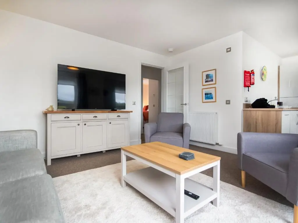 a living room with a couch and a table and a tv at Thistledown in Dornoch