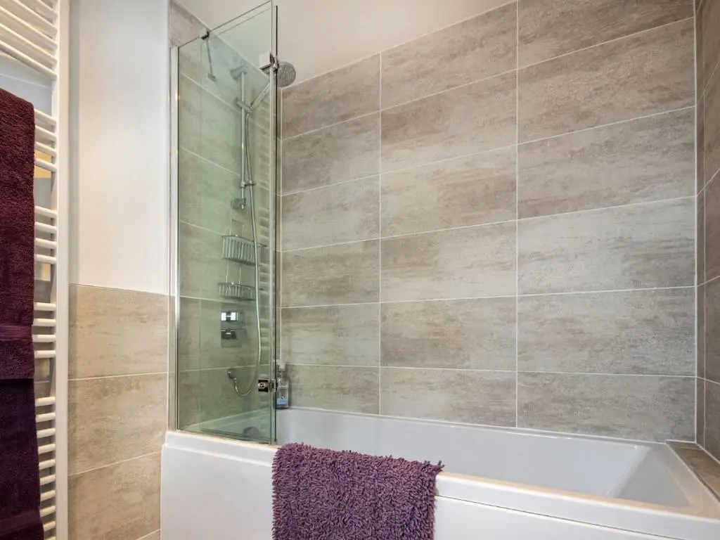 a bathroom with a tub and a glass shower at Thistledown in Dornoch