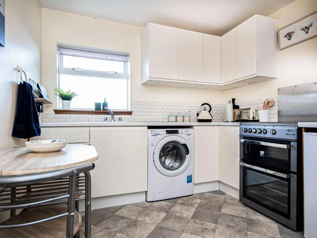 a kitchen with a washing machine and a table at Sunnyside Cottage in Embo
