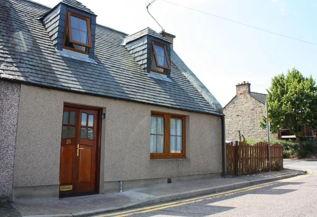 a house with a brown door and windows on a street at 23 Fairfield in Inverness