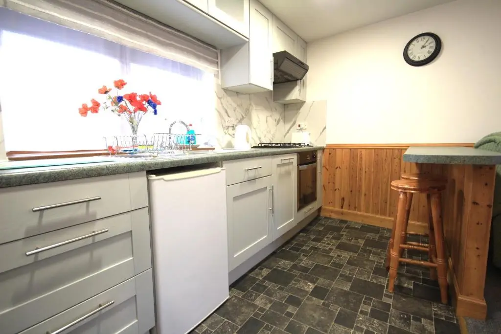 a kitchen with white cabinets and a clock on the wall at 23 Fairfield in Inverness