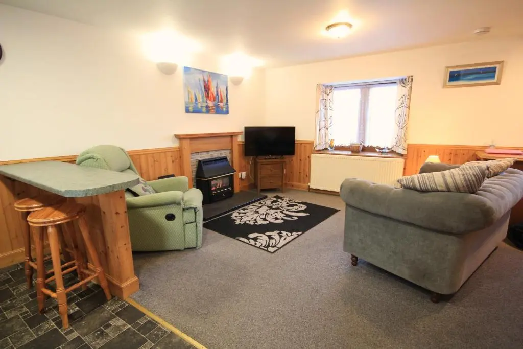 a living room with a couch and chairs and a television at 23 Fairfield in Inverness